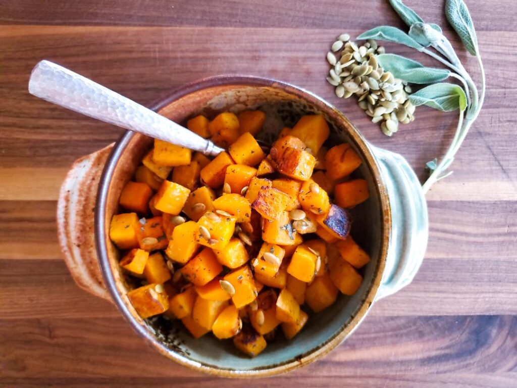Golden orange butternut squash is roasted in the oven until lightly charred, then sprinkles with sage and pumpkin seeds.