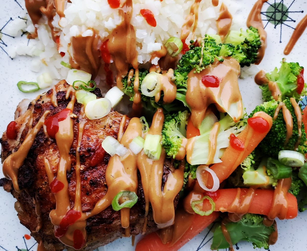 Creamy peanut sauce drizzled over steamed carrots and broccoli, grilled chicken, and cauliflower rice.