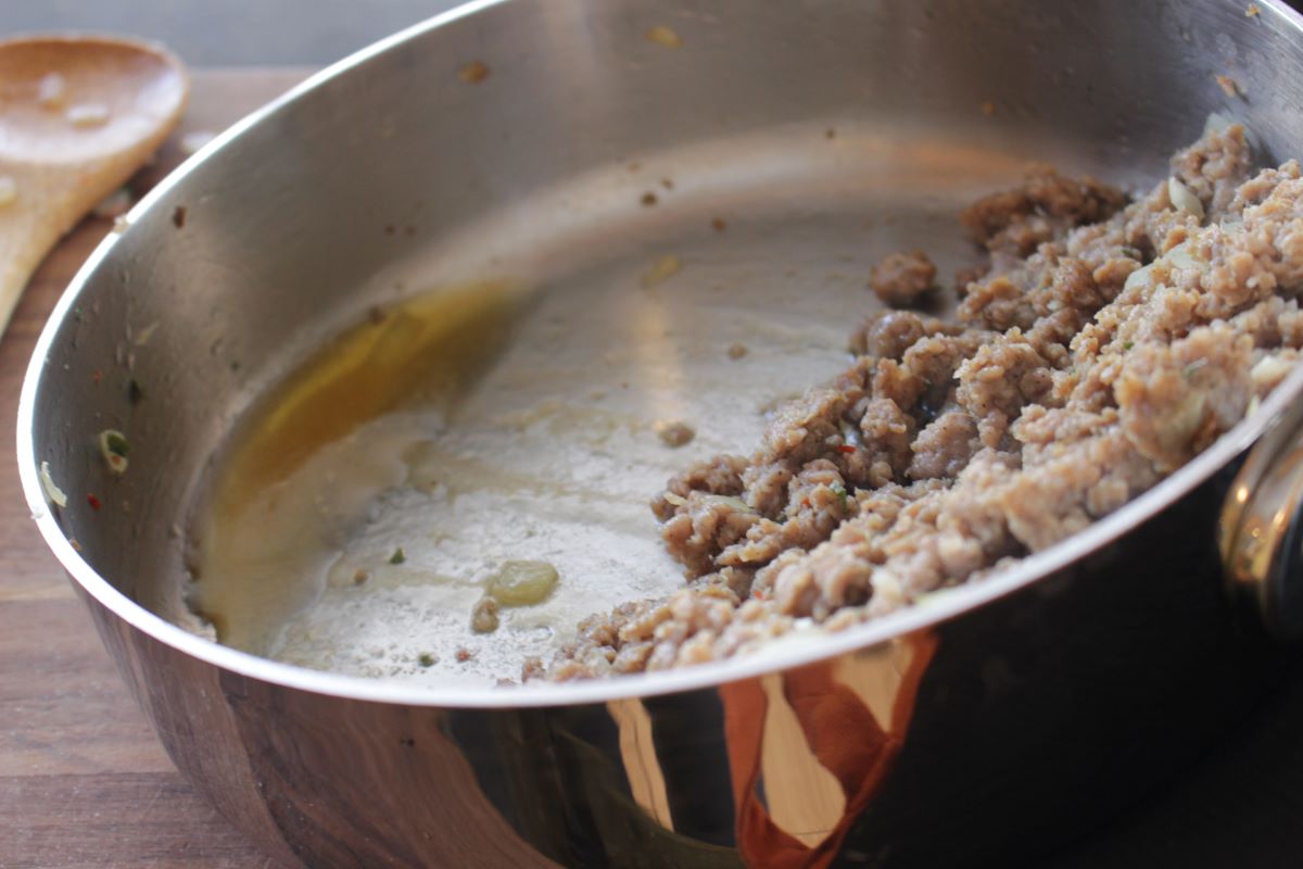 Drain the grease off your sausage by tilting the pan. Move the cooked sausage to the top of the pan. Using your spatula press the sausage to get the excess grease out of the meat.