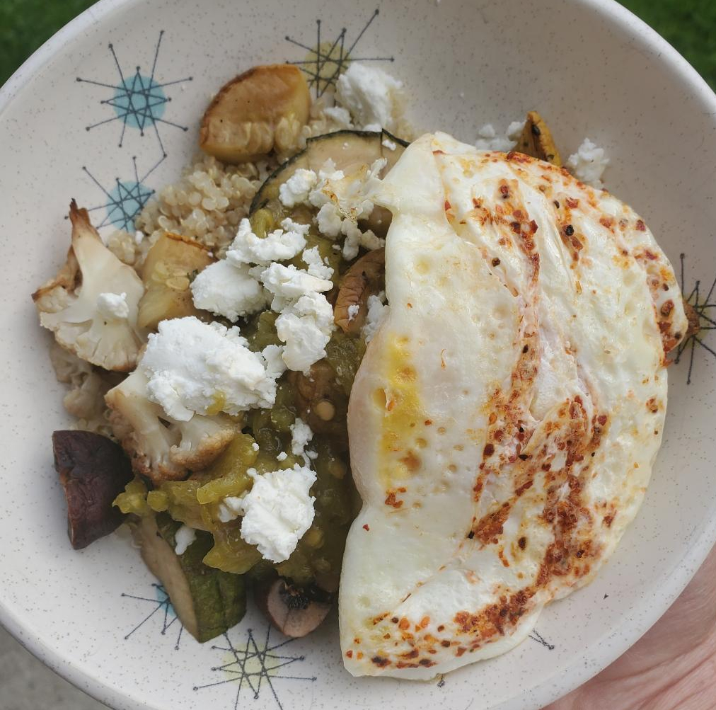 Smoked veggie leftovers are repurposed into a breakfast bowl with quinoa, goat cheese, and a fried egg.