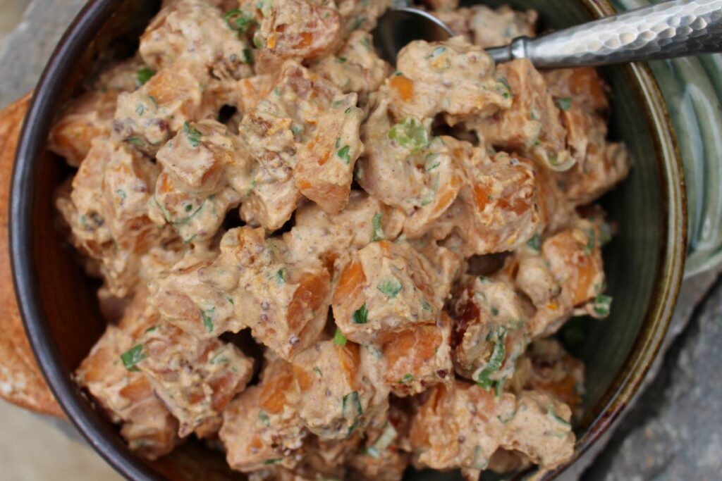 Cubed sweet potatoes with a dressing of greek yogurt and adobo sauce. This potato salad has green onions and bacon mixed in as well.