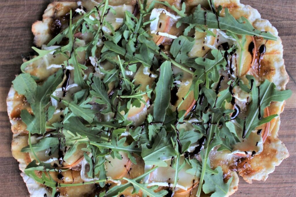 peach and brie grilled pizza topped with arugula and balsamic reduction