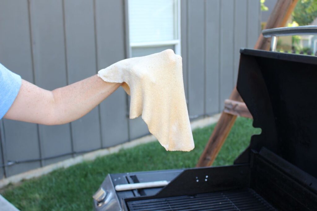 Use the back of your hand to brign the pizza dough out to the grill to prevent tearing.