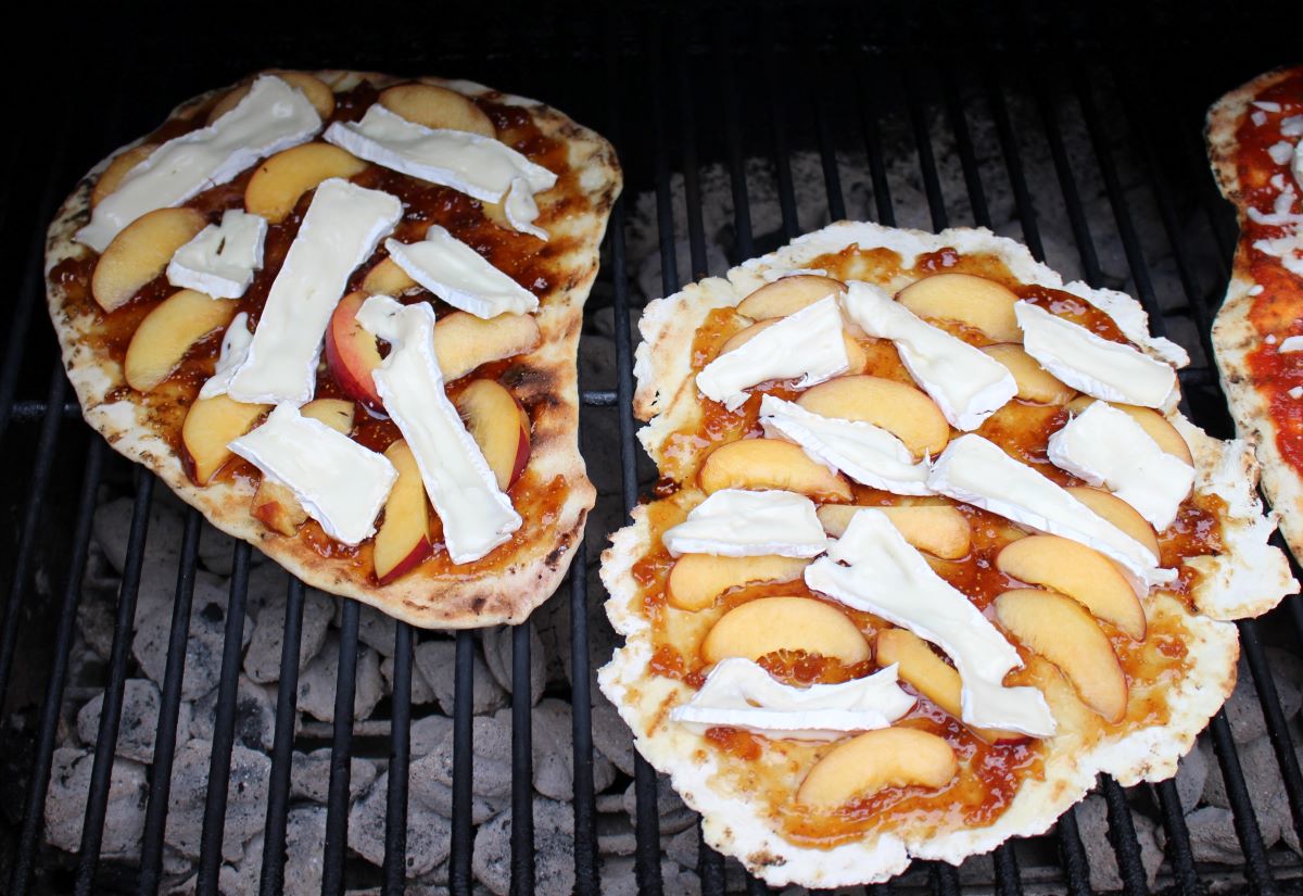 Two peach and brie pizzas on the grill.