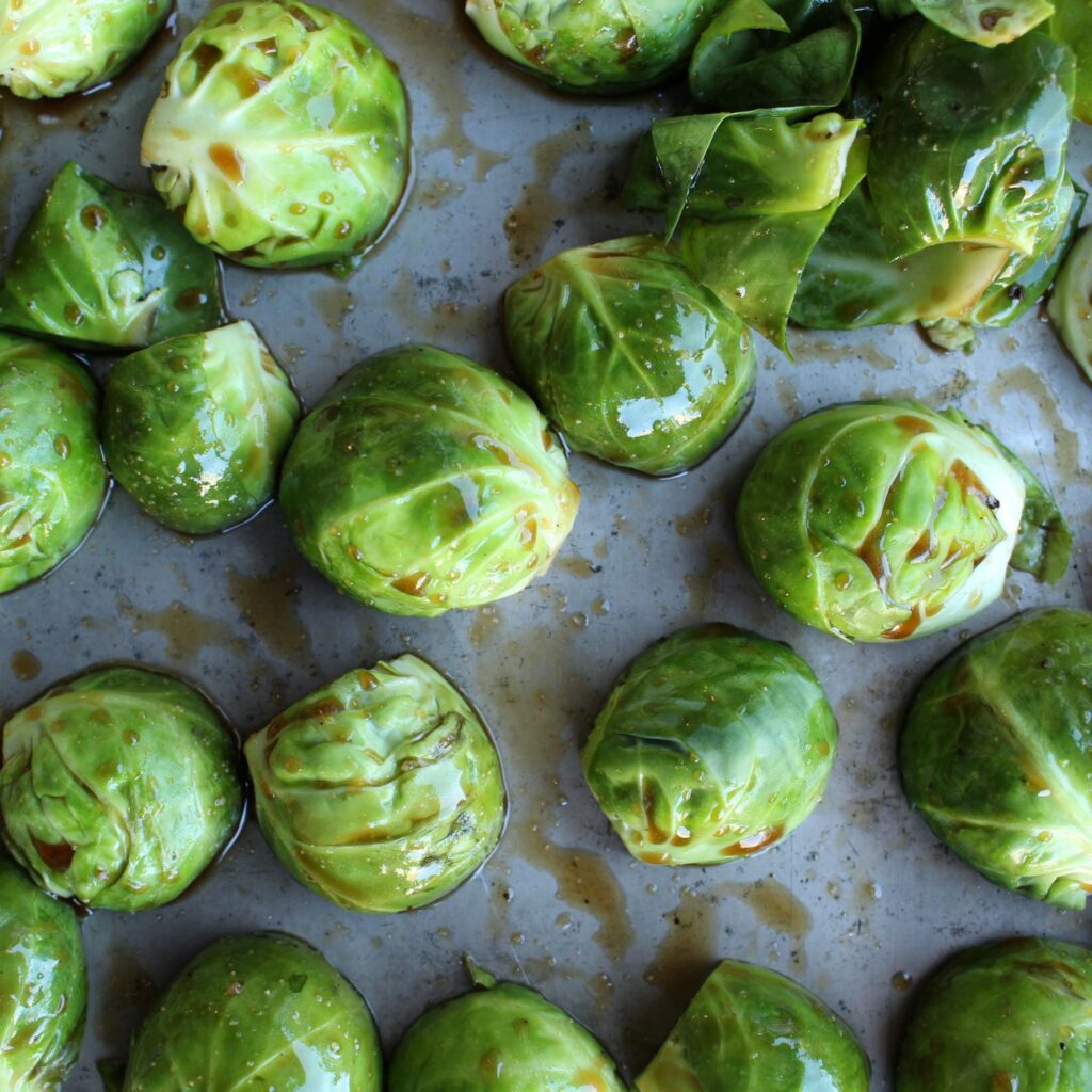 Halved marinated Brussels on a pan, cut side down.on pa