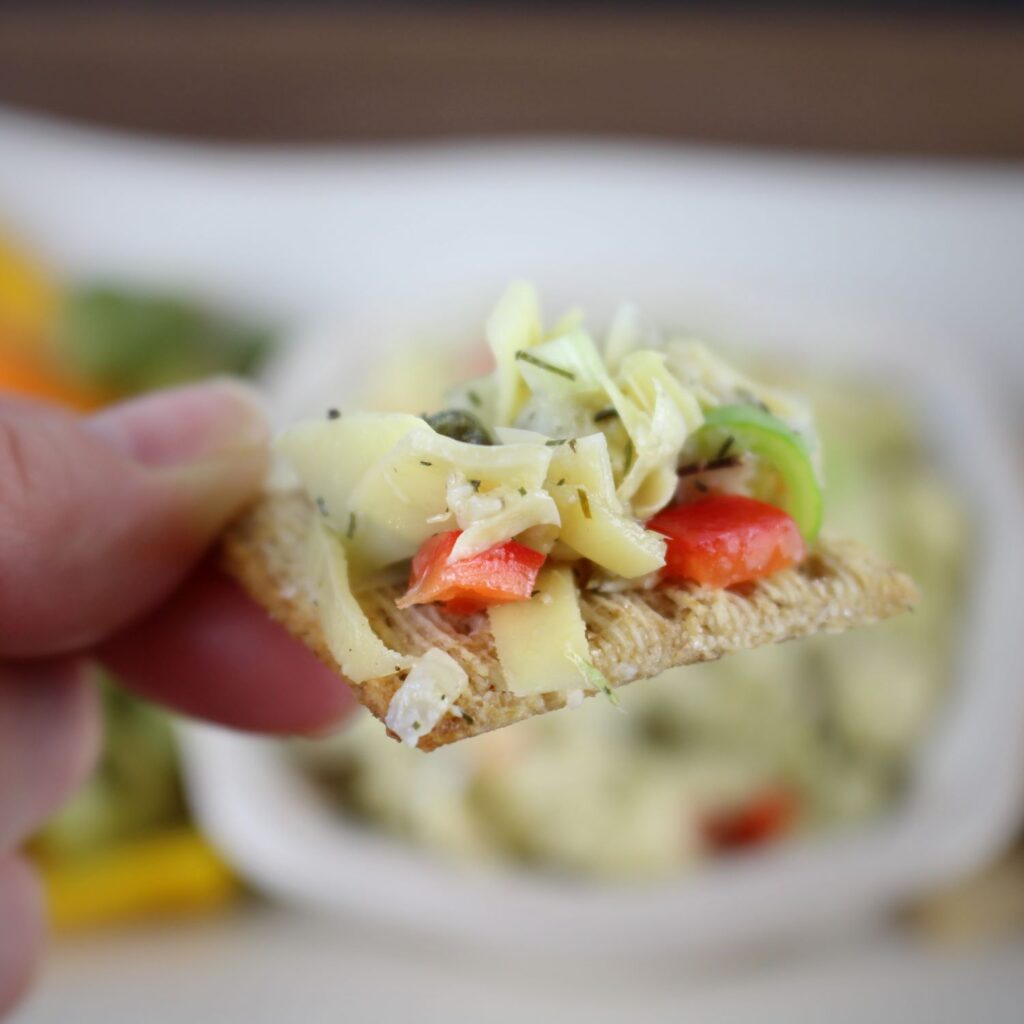 Chunky artichoke dip on a triscuit