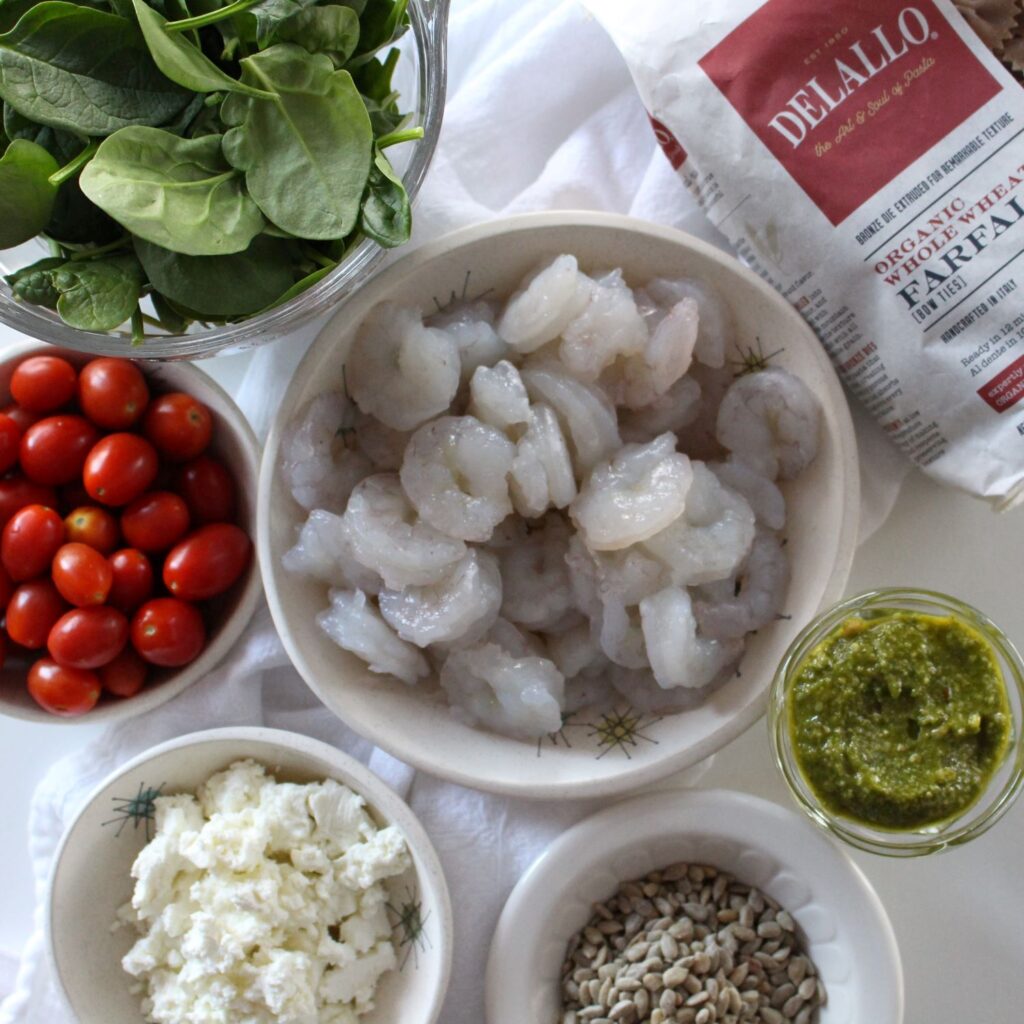 shrimp, pesto, cherry tomatoes, bowtie pasta, goat cheese, spinach, sunflower seeds are all the ingredients you need for this light creamy pasta dish.
