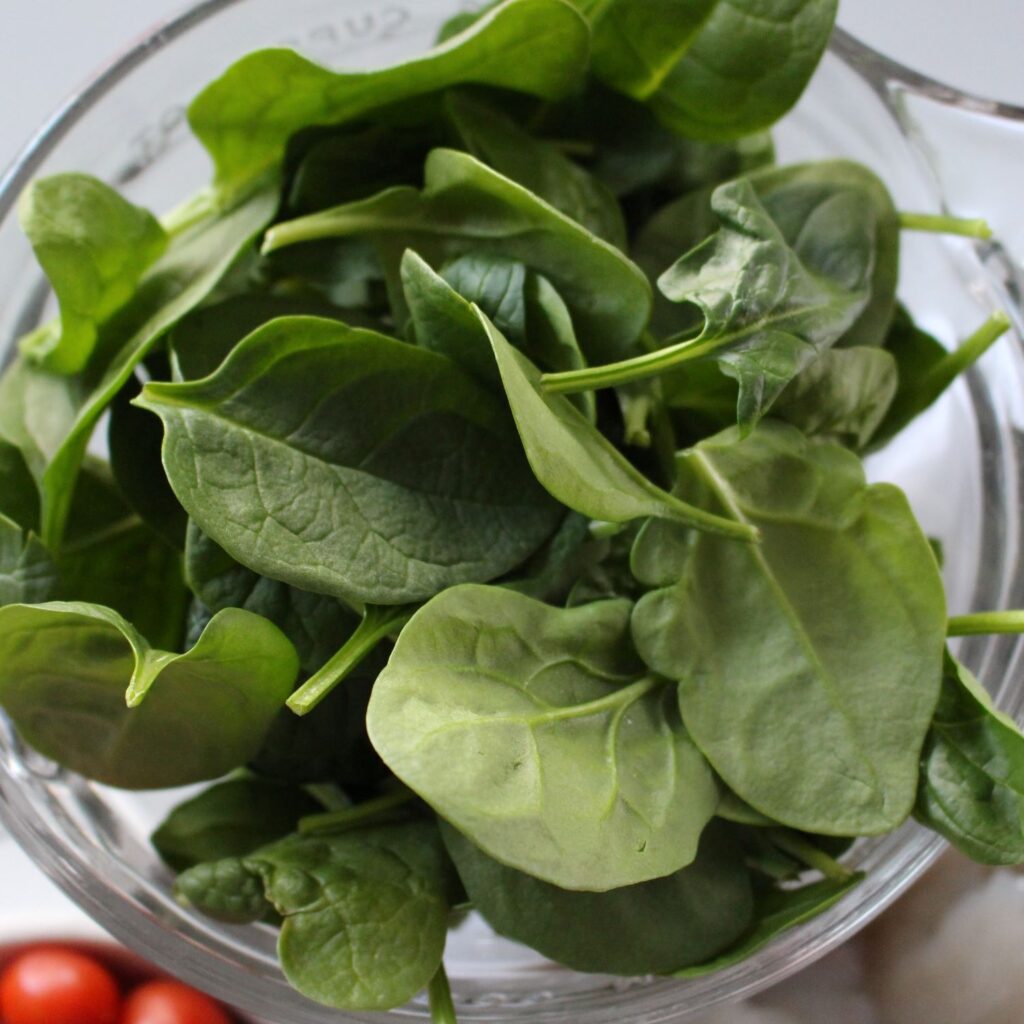 Fresh Spinach in a glass bowl ready to be tossed in to the pasta.