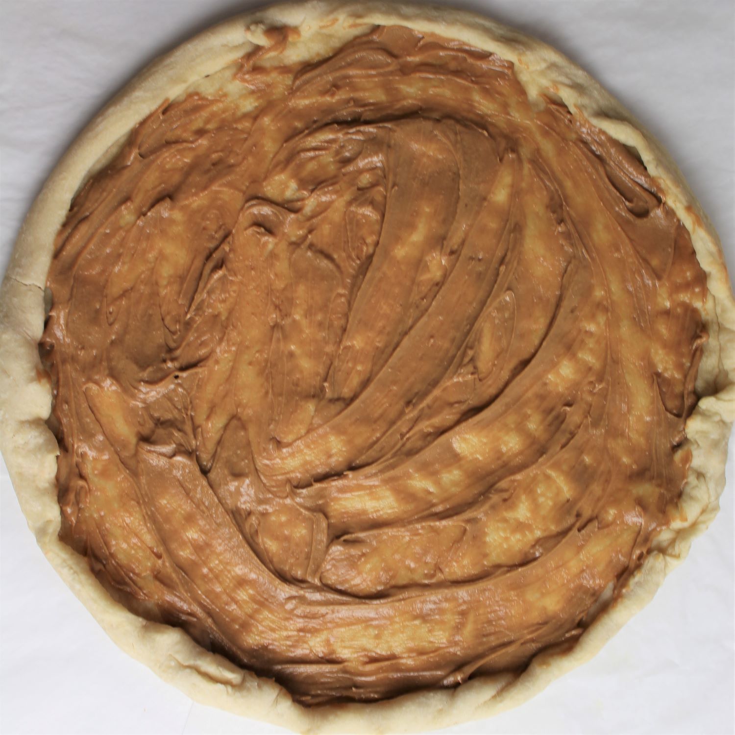 par-baked crust covered with peanut sauce