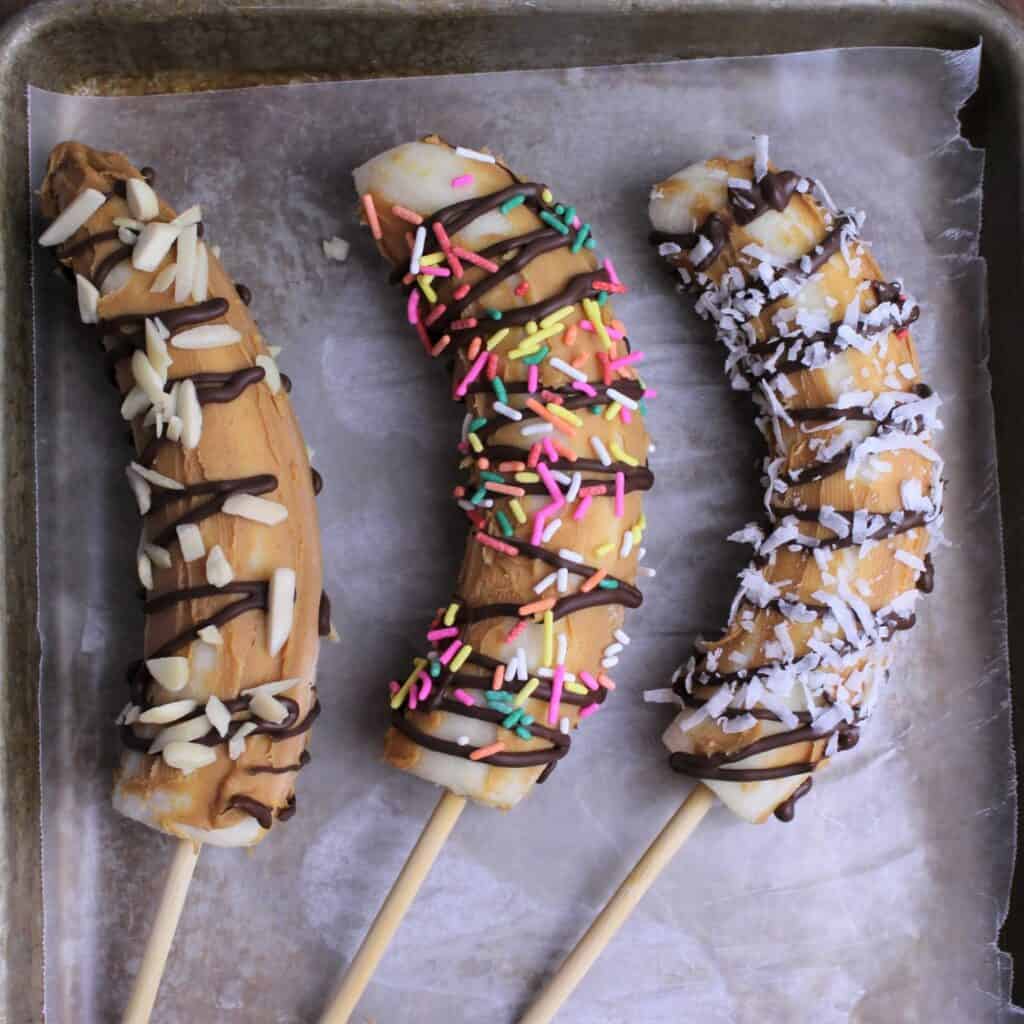 Whole bananas on skewers slathered in peanut butter, drizzled with chocolate, and sprinkled with toppings