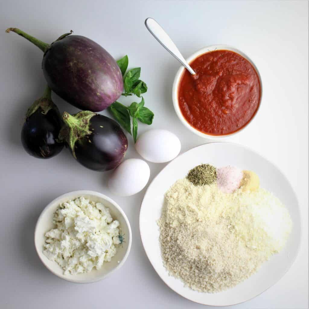 all ingredients for eggplant parmesan, breading, eggplants, pizza sauce, and goat cheese.