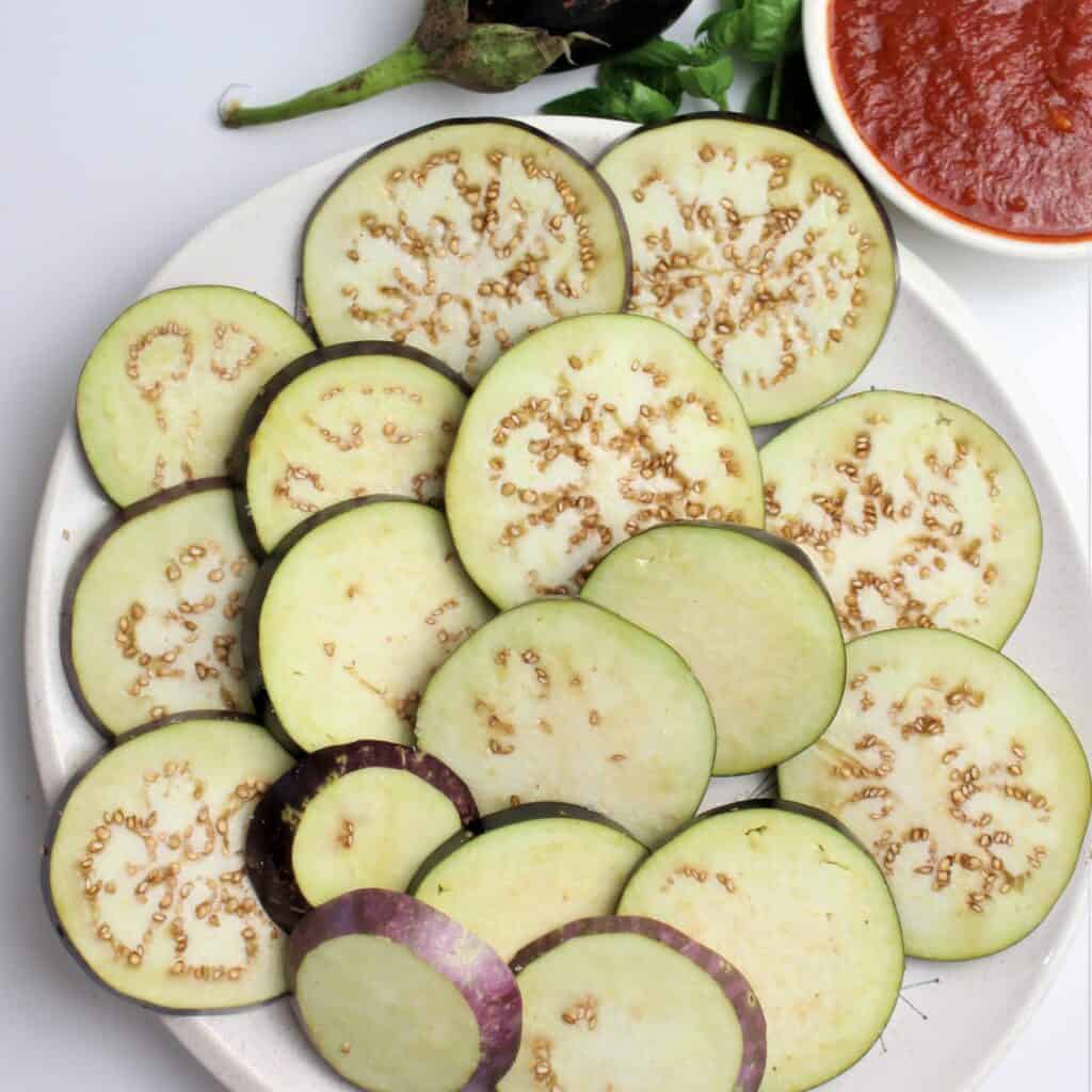 sliced eggplant on platter before being breaded