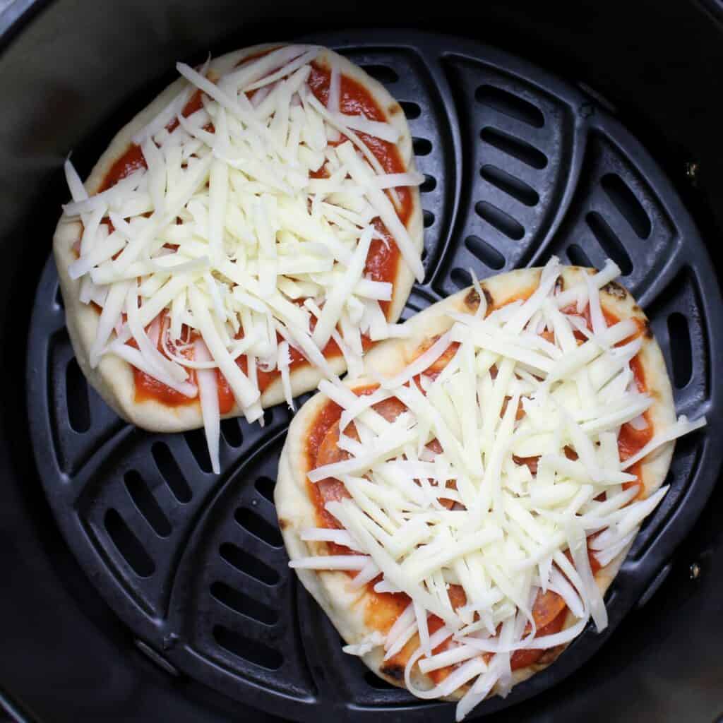 2 naan pizzas in the air fryer ready to cook.