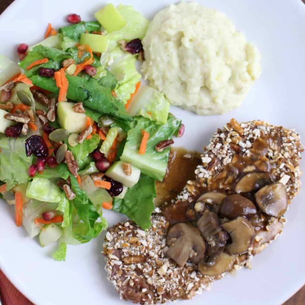 pretzel encrusted schnitzel plated with a autumn salad and mashed cauliflower.