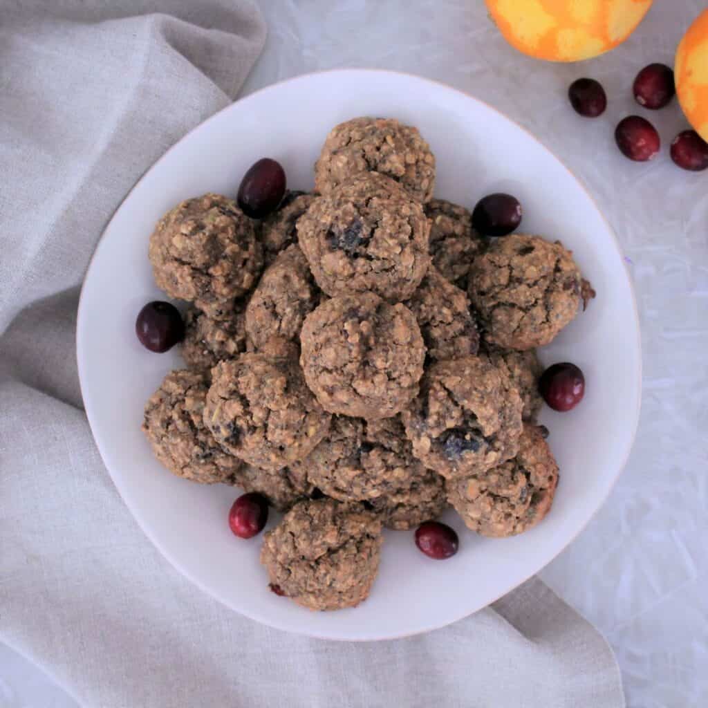 cranberry pistachio oatmeal cookies on a plate with fresh cranberries for garnish
