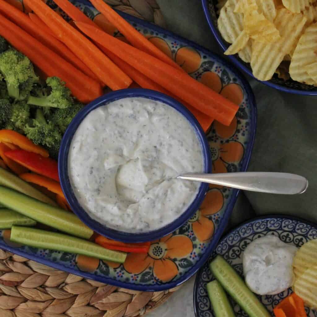 healthy ranch dip with a platter of cut veggies and potato chips.