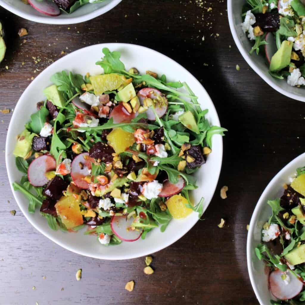 white bowls with this colorful beet salad drizzled with balsamic vinaigrette.