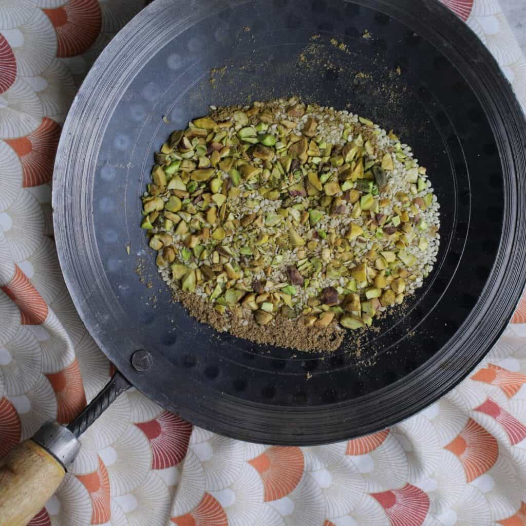 Dukkah toasted in a pan. Dukkah is a Middle Eastern condiment that is made up of toasted nuts, seeds and spices.