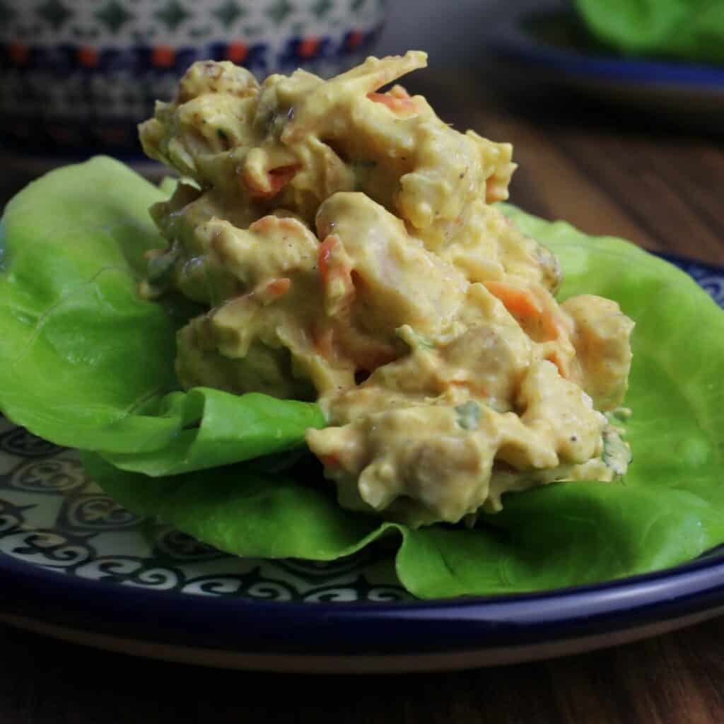 A spoonful of Healthy curry chicken salad without celery in a butter lettuce cup.