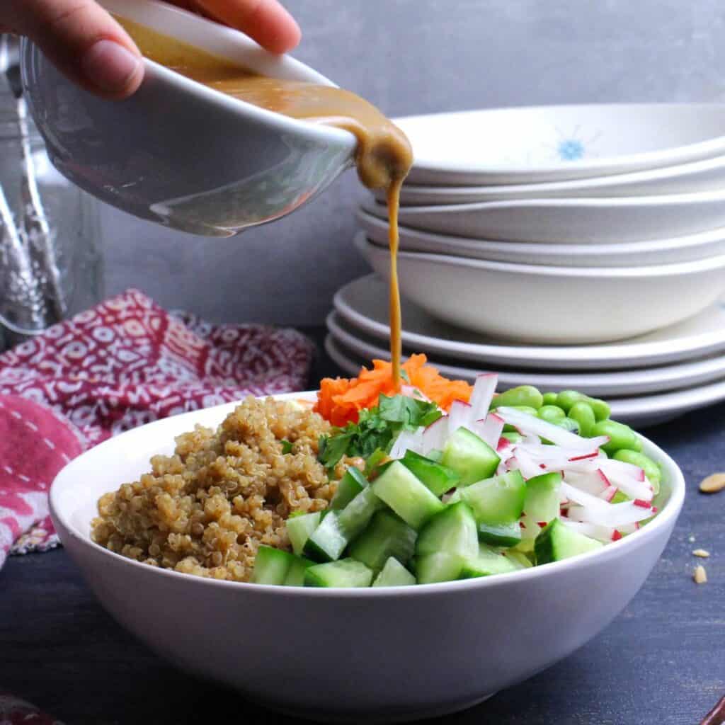 Sweet and savory peanut dressing being drizzled over the Thai Nourish Bowl.