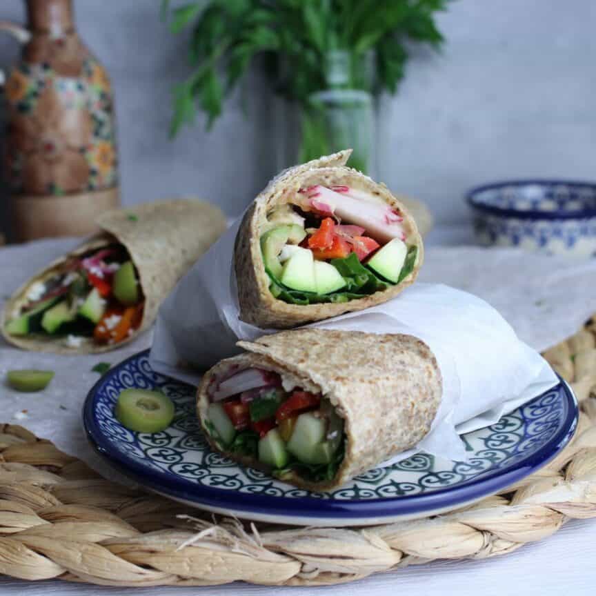 Whole grain tortilla spread with hummus, layered with veggies, and sprinkled with feta and olives. Rolled up for one delicious crunchy wrap.