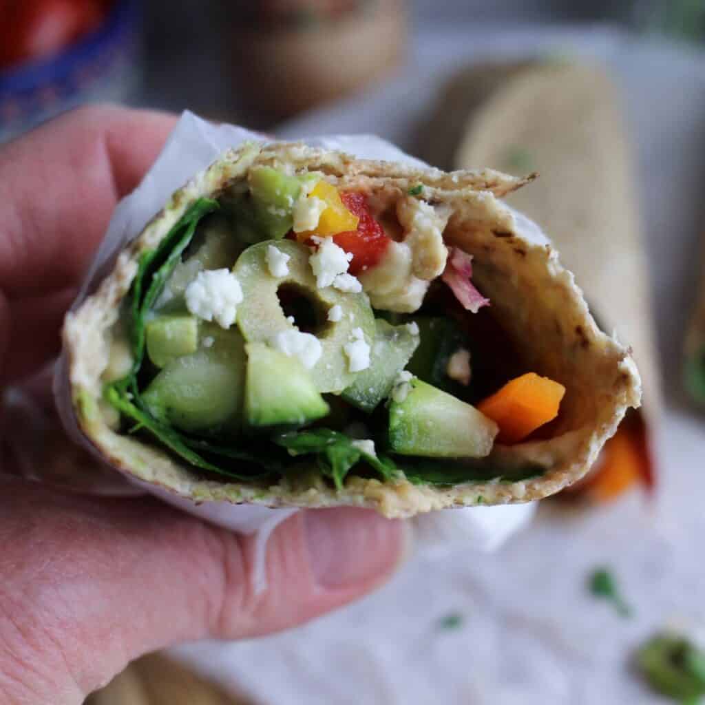 Mediterranean Veggie Wrap with Olives and Hummus rolled up and ready for a big bite.
