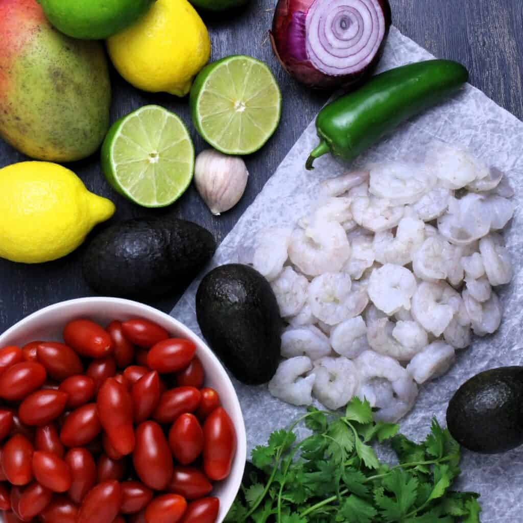 All the ingredients you need to make this light and refreshing ceviche: shrimp, lime & lemon juices, tomatoes, mangoes, garlic, cilantro, onion, jalapeno, and avocado.