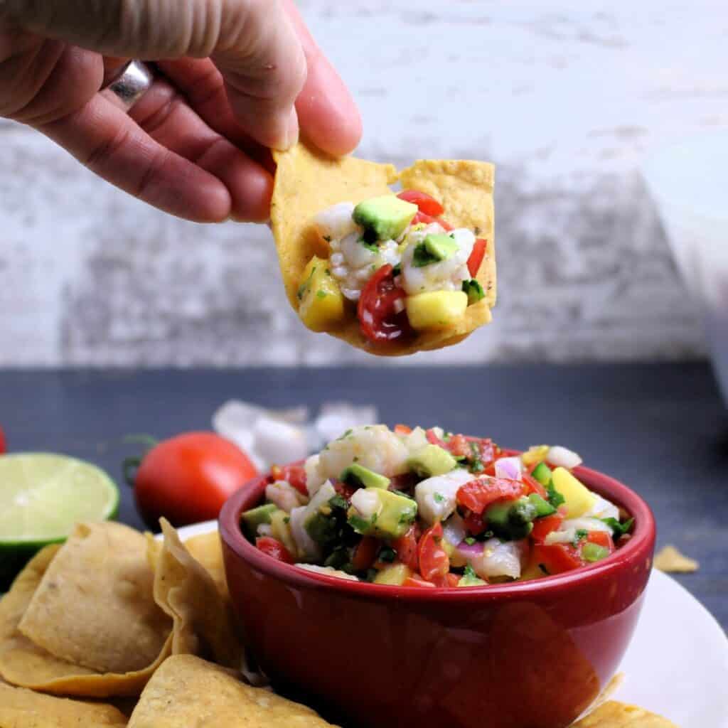 Sturdy tortilla chips scooping up a bite of Mango Shrimp Ceviche with Avocado.