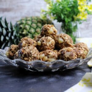 Pina Colada Energy Balls plated with whole pineapple behind plate.