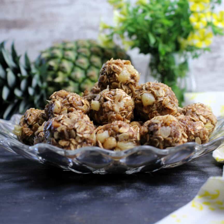 Pina Colada Energy Balls plated with whole pineapple behind plate.