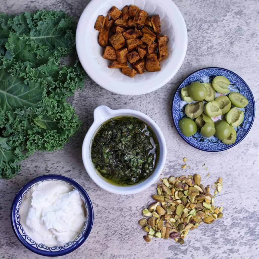 This Nourish Bowl can be made with leftovers: roasted sweet potatoes, Greek yogurt, kale, olives, chimichurri, and pistachios.