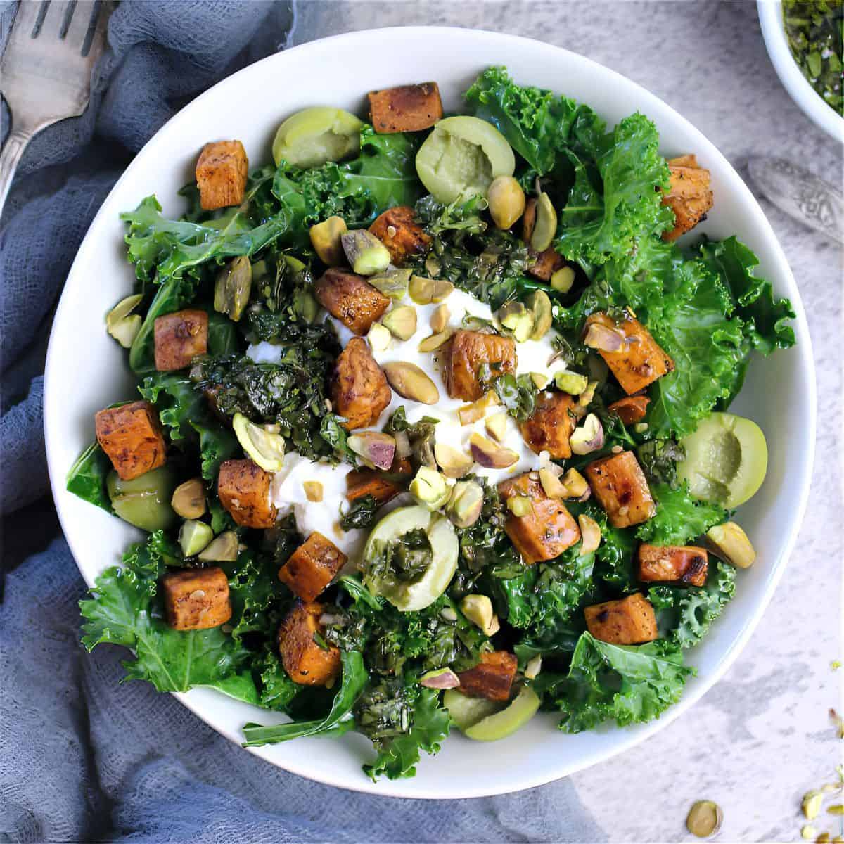 Feel good Nourish Bowl with kale, Greek yogurt, olives, pistachios, sweet potatoes, and topped with chimichurri.