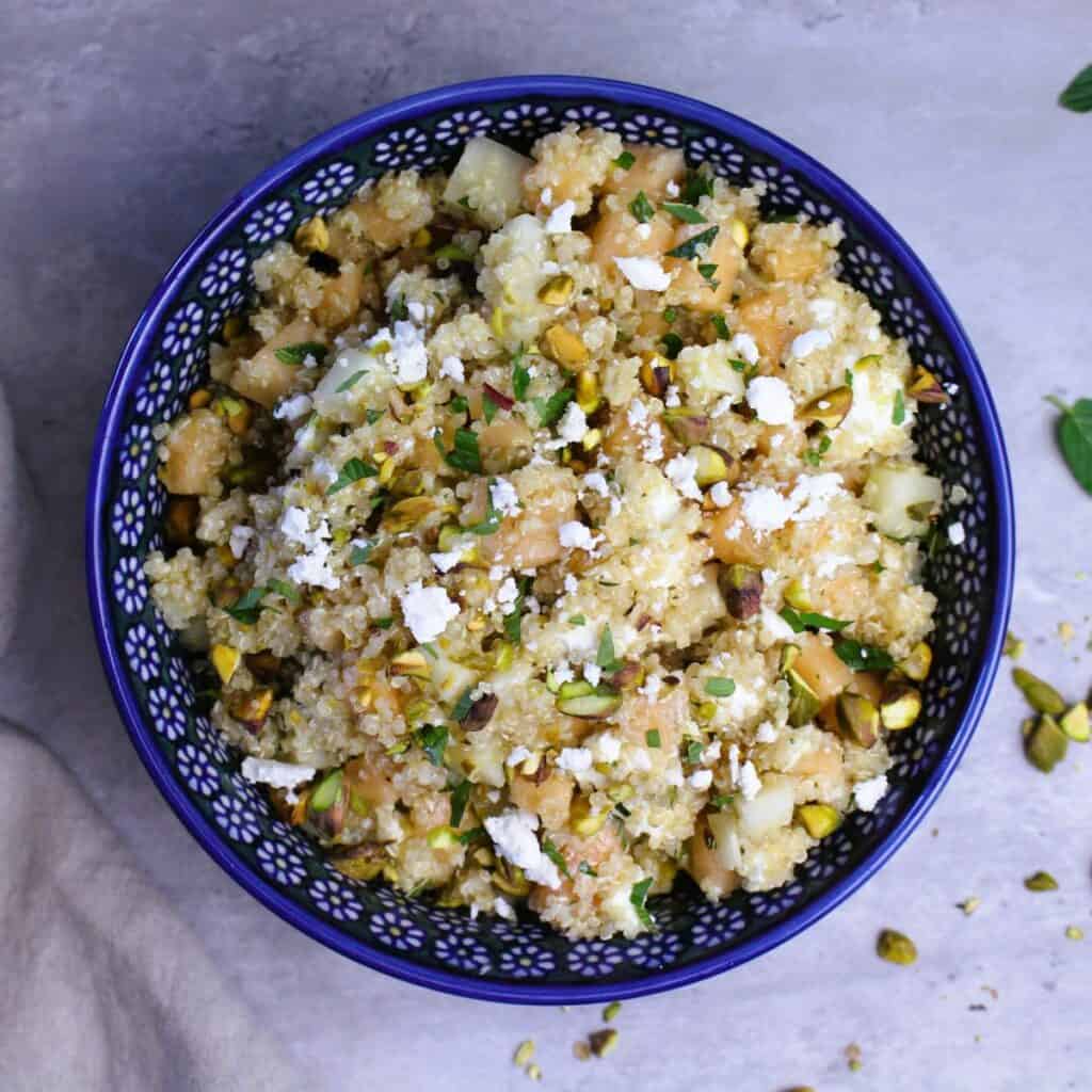 Refreshing cold quinoa salad with cantaloupe and goat  cheese topped with pistachios