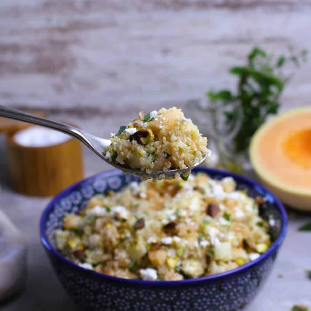 Spoonful of quinoa salad with cantaloupe and goat cheese.