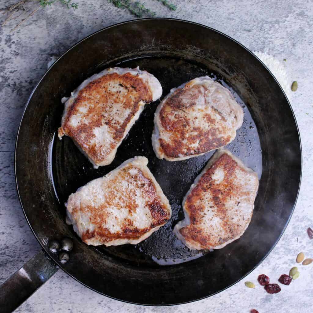 Seared pork loin chops in pan that can go from stove top to oven.