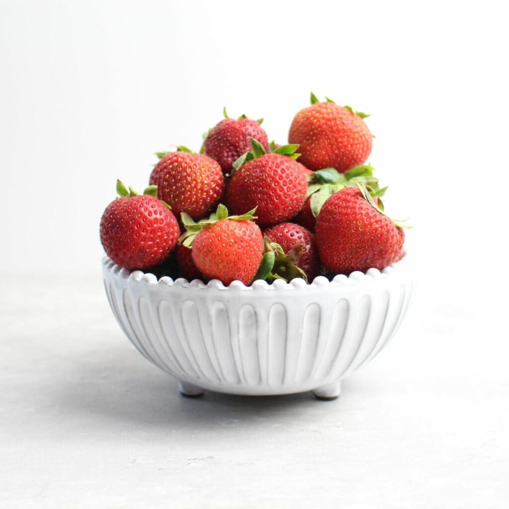 Ripe strawberries in white dish.