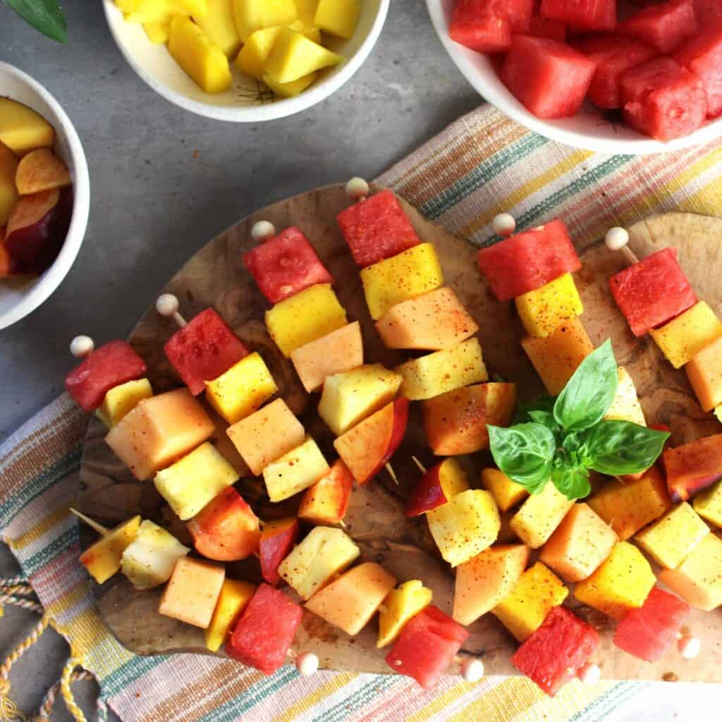 Platter of fruit skewers with tajin sprinkled on top.