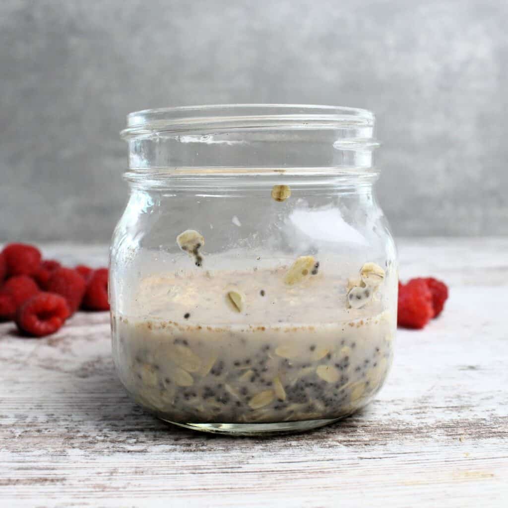 Almond milk, maple syrup, and vanilla poured into glass jar with oat mixture.