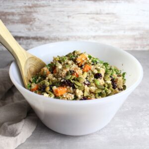 Autumn flavors mixed with quinoa in a serving bowl with large wooden spoon.