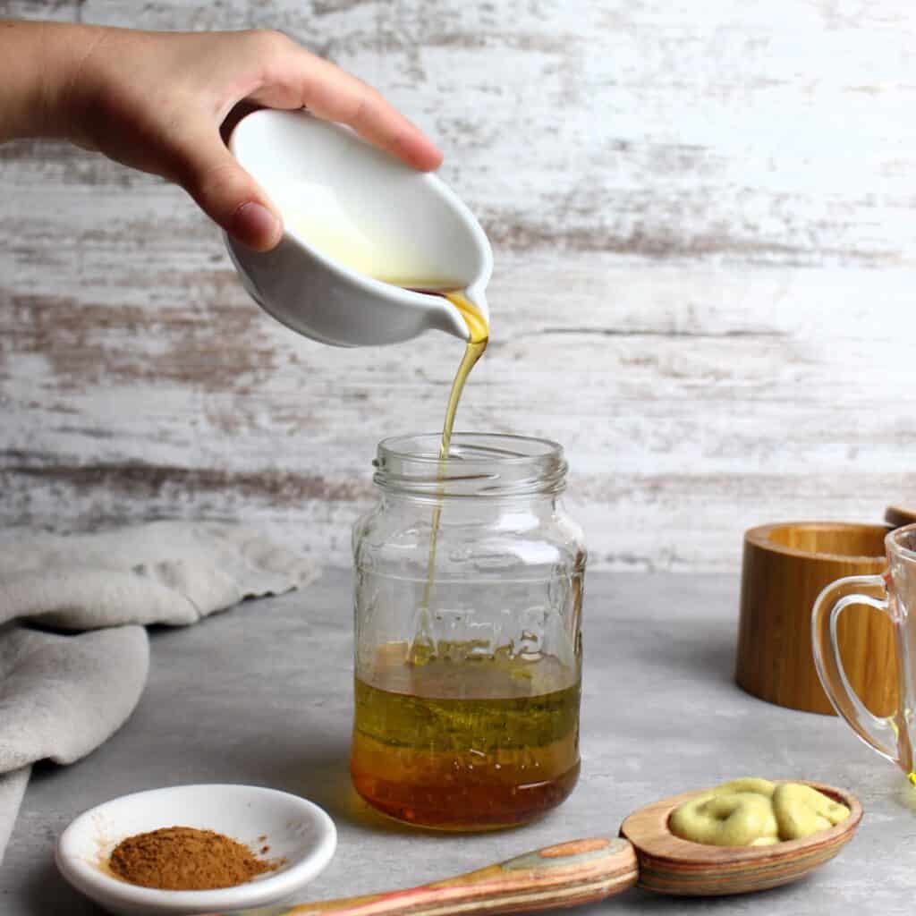 Maple syrup being poured into a jar for the Cinnamon Maple Vinaigrette dressing.