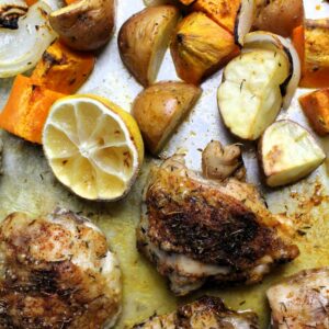 Tray baked chicken thighs and root veggies with lemon half right out of the oven.