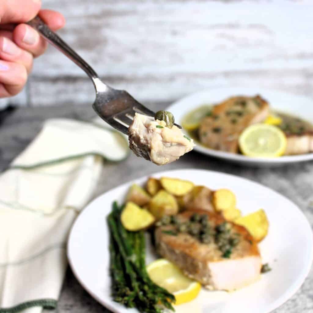 Forkful of pork piccata with capers.