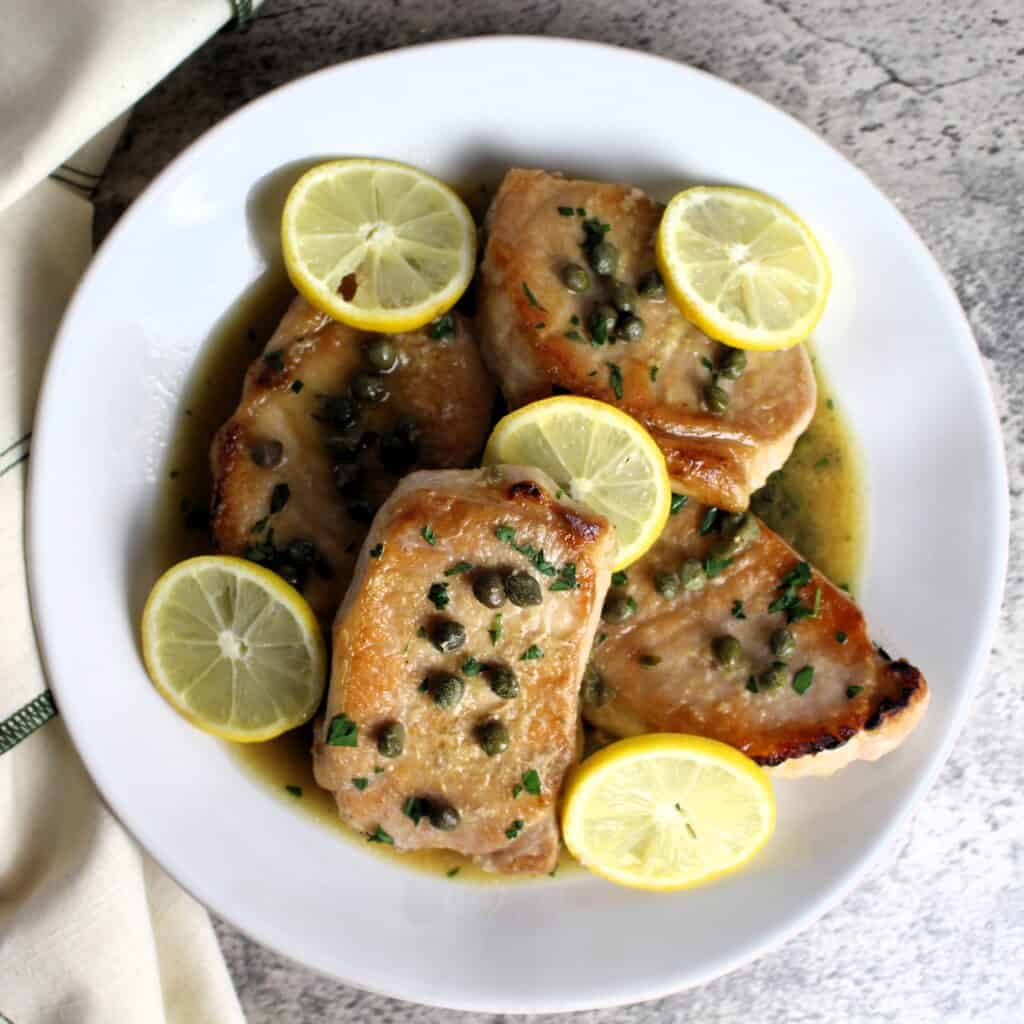 Pork Piccata on serving plate with lemon slices.