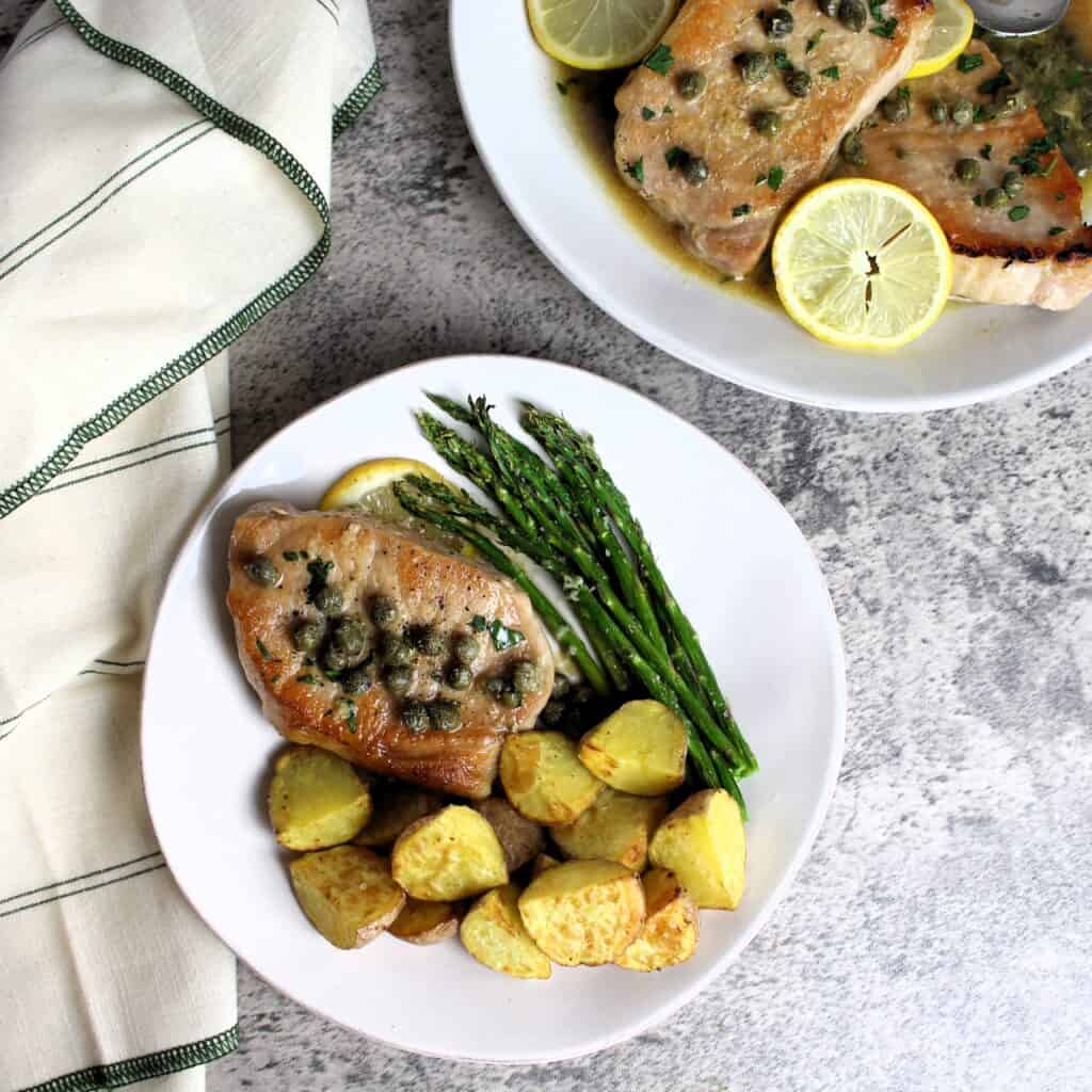 Pork piccata plated with asparagus and roasted potatoes.