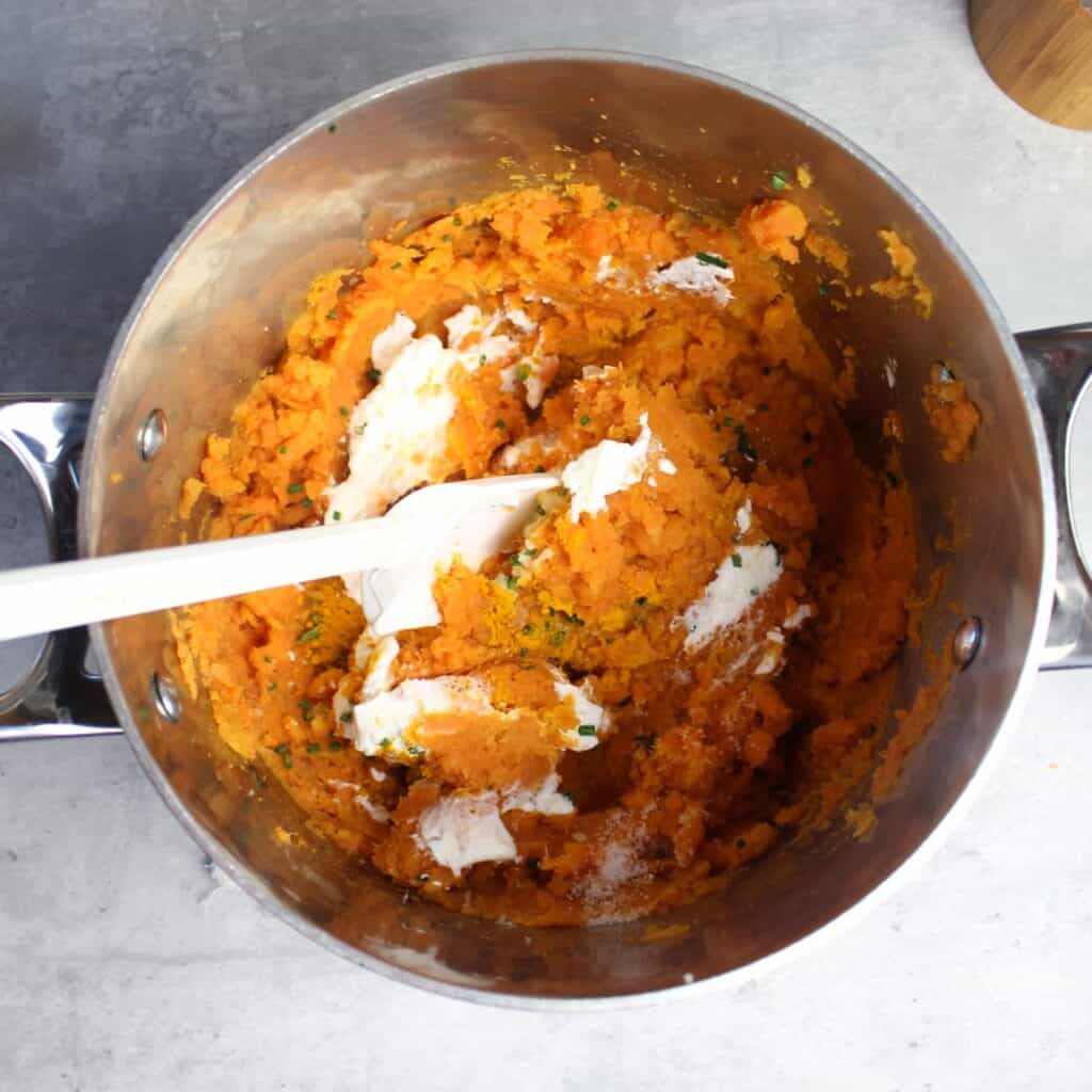 Folding in the rest of the ingredients to the sweet potatoes.