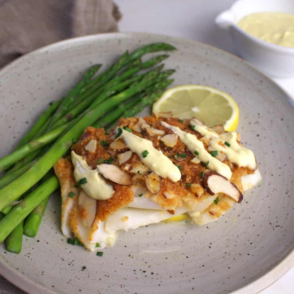 Almond encrusted cod baked to perfection drizzled with Greek yogurt hollandaise sauce and a side of asparagus.