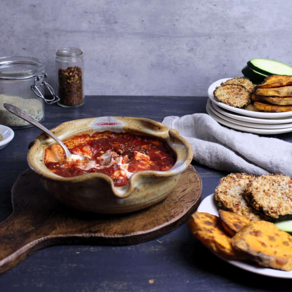 Baked Goat Cheese with Marinara dip with plates of air-fried sweet potatoes, eggplant, and raw zucchini slices.