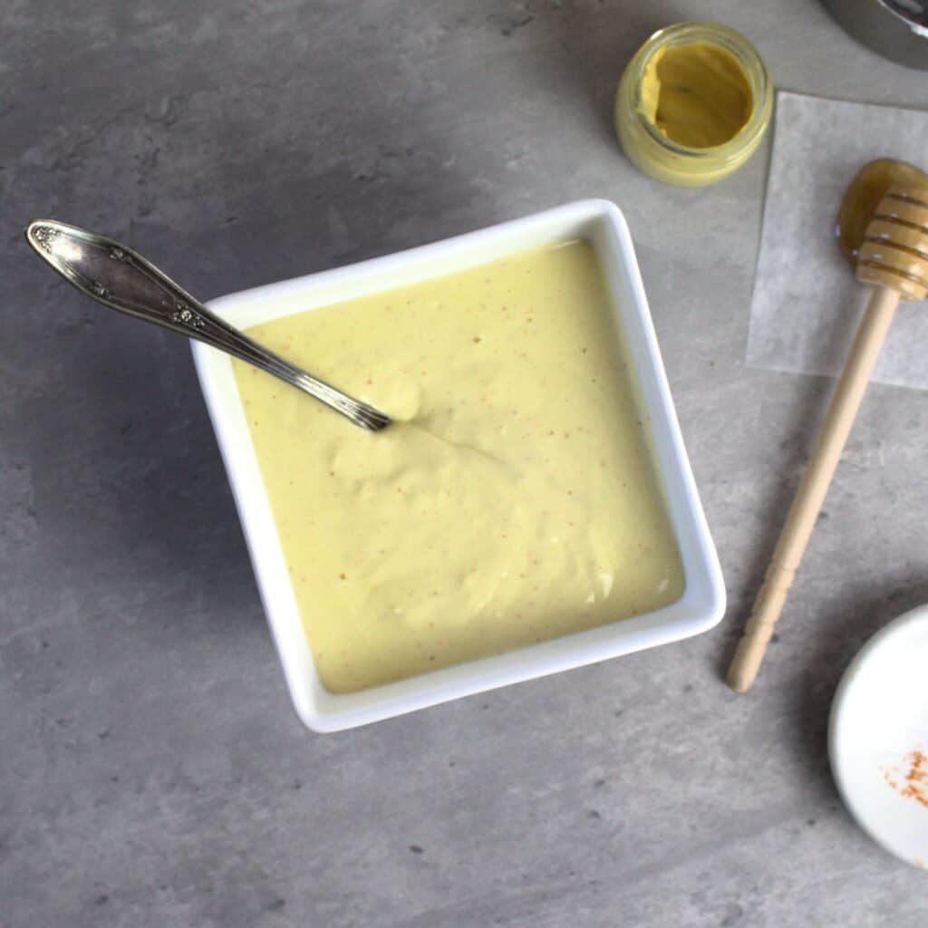 Hollandaise sauce with Greek yogurt in bowl with spoon ready to serve.