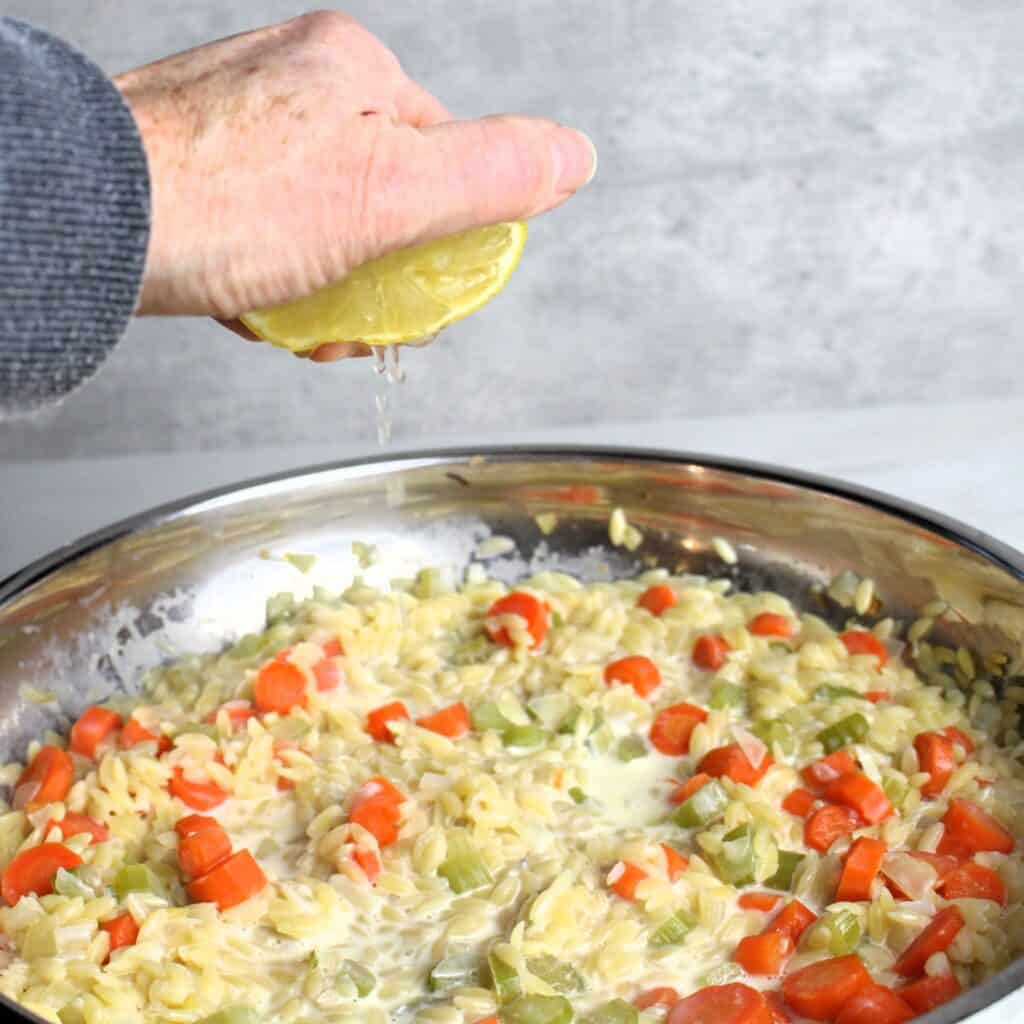 Squeezing lemon into chicken orzo bake.